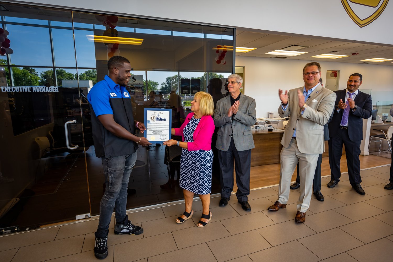 Town of Islip Supervisor Angie Carpenter presented Fignole Cosmeus with a citation after he saved a life. Michael Brown, Owner, Empire Auto Group (tan suit) joined in.